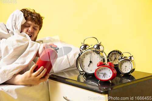 Image of Man wakes up and he\'s mad at clock ringing, switches it off with the extinguisher