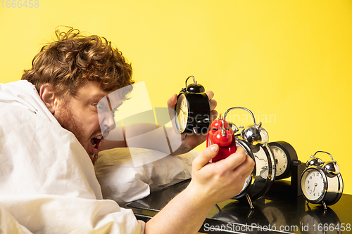 Image of Man wakes up and he\'s mad at clock ringing, switches it off by breaking down