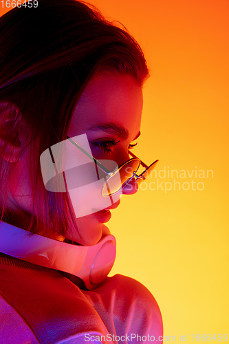 Image of Caucasian woman\'s portrait isolated on orange studio background in multicolored neon light