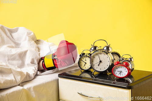 Image of Man wakes up and he\'s mad at clock ringing, switches it off with the boxing glove