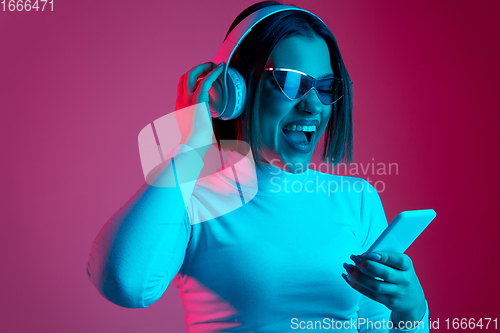 Image of Caucasian woman\'s portrait isolated on pink studio background in multicolored neon light