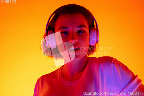 Image of Caucasian woman\'s portrait isolated on orange studio background in multicolored neon light