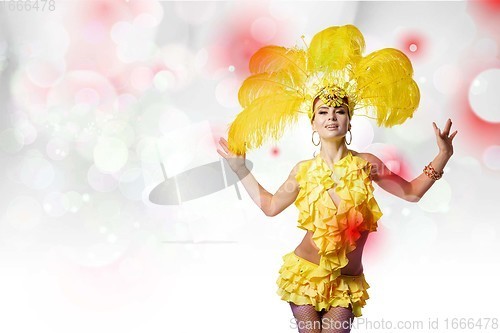 Image of Beautiful young woman in carnival, stylish masquerade costume with feathers dancing on white studio background with shining bokeh