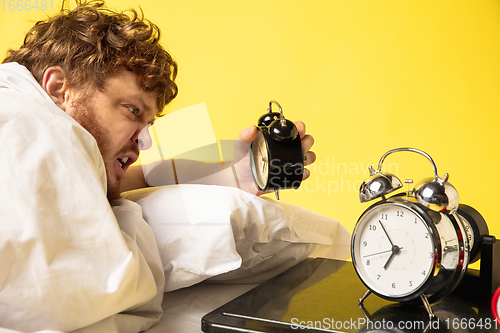 Image of Man wakes up and he\'s mad at clock ringing, switches it off screaming