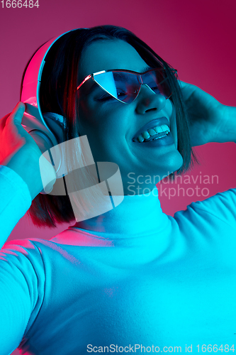 Image of Caucasian woman\'s portrait isolated on pink studio background in multicolored neon light