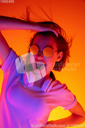 Image of Caucasian woman\'s portrait isolated on orange studio background in multicolored neon light