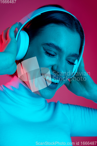 Image of Caucasian woman\'s portrait isolated on pink studio background in multicolored neon light