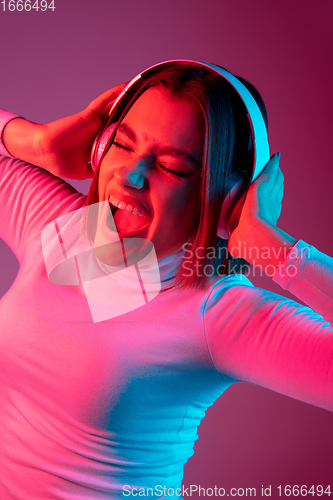 Image of Caucasian woman\'s portrait isolated on pink studio background in multicolored neon light