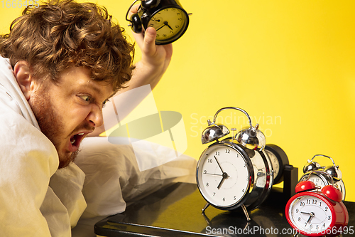 Image of Man wakes up and he\'s mad at clock ringing, switches it off by breaking down