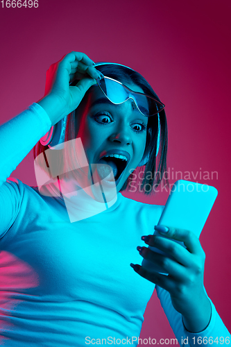 Image of Caucasian woman\'s portrait isolated on pink studio background in multicolored neon light