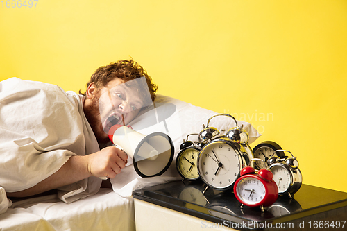 Image of Man wakes up and he\'s mad at clock ringing, switches it off by breaking down with megaphone