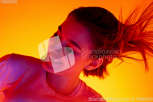 Image of Caucasian woman\'s portrait isolated on orange studio background in multicolored neon light