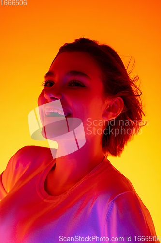 Image of Caucasian woman\'s portrait isolated on orange studio background in multicolored neon light