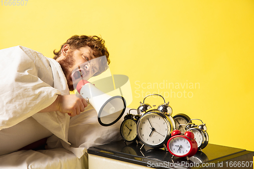 Image of Man wakes up and he\'s mad at clock ringing, switches it off by breaking down with megaphone