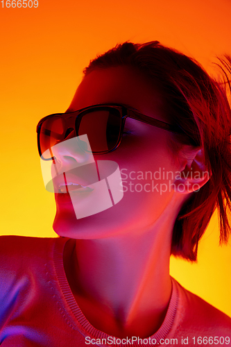 Image of Caucasian woman\'s portrait isolated on orange studio background in multicolored neon light