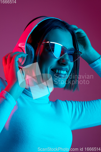 Image of Caucasian woman\'s portrait isolated on pink studio background in multicolored neon light