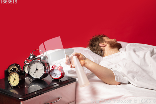 Image of Man wakes up and he\'s mad at clock ringing, switches it off with water spraying