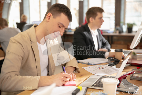 Image of Young caucasian colleagues working together in a office using modern devices and gadgets