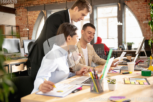 Image of Young caucasian colleagues working together in a office using modern devices and gadgets