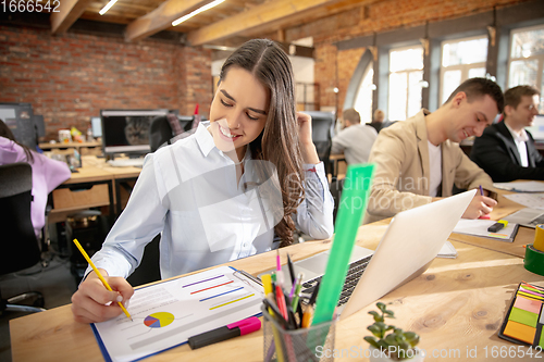 Image of Young caucasian colleagues working together in a office using modern devices and gadgets