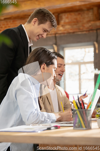 Image of Young caucasian colleagues working together in a office using modern devices and gadgets