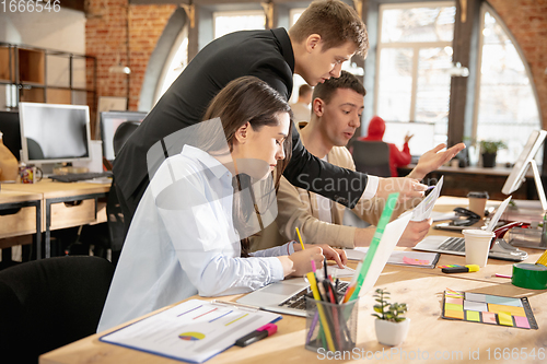 Image of Young caucasian colleagues working together in a office using modern devices and gadgets