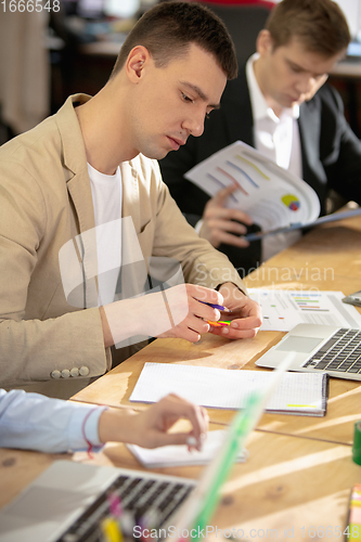 Image of Young caucasian colleagues working together in a office using modern devices and gadgets