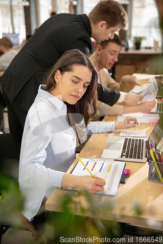 Image of Young caucasian colleagues working together in a office using modern devices and gadgets