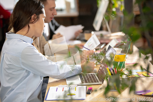 Image of Young caucasian colleagues working together in a office using modern devices and gadgets