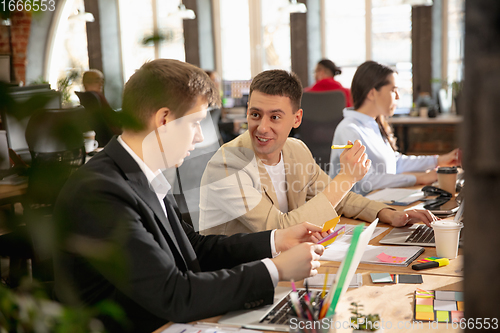 Image of Young caucasian colleagues working together in a office using modern devices and gadgets