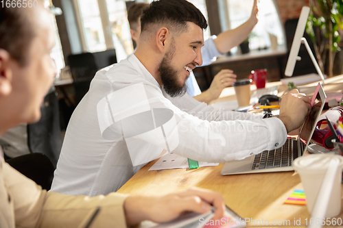 Image of Young caucasian colleagues working together in a office using modern devices and gadgets