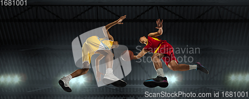 Image of Young basketball players in competitive fight, motion in flight on black background, look from the bottom. Concept of sport, movement, energy and dynamic.