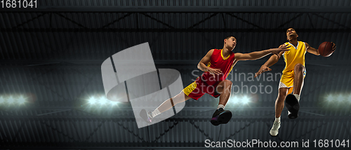 Image of Young basketball players in competitive fight, motion in flight on black background, look from the bottom. Concept of sport, movement, energy and dynamic.