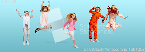 Image of Group of elementary school kids or pupils jumping in colorful casual clothes on blue studio background. Creative collage.