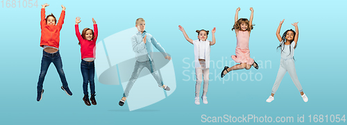 Image of Group of elementary school kids or pupils jumping in colorful casual clothes on blue studio background. Creative collage.