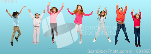 Image of Group of elementary school kids or pupils jumping in colorful casual clothes on blue studio background. Creative collage.