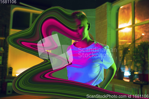Image of Portrait of stylish woman in neon lighted interior. The face is smeared, sucked into the screen. The concept of social network dependency