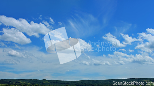 Image of Beautiful cloudscape over a wooded hilly countryside in fine sum