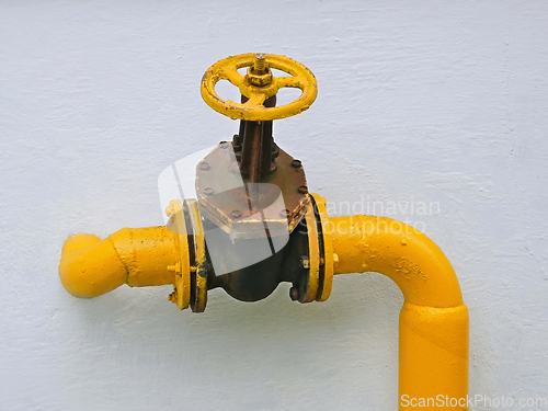 Image of Old gas valve on the pipe goes into the vertical wall