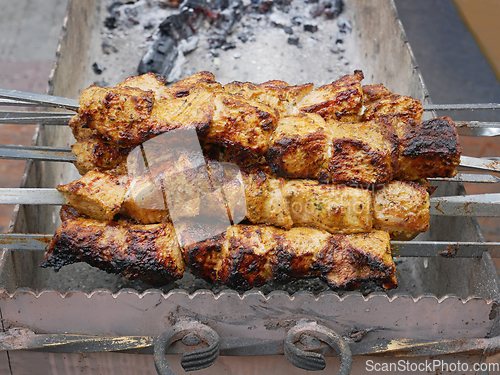 Image of Meat strung on metal skewers fried on charcoal outdoors