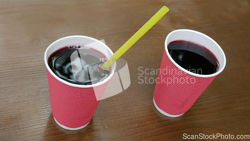 Image of Two pink paper cups with a drink standing on a lacquered wooden 