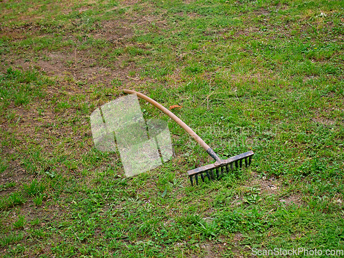 Image of Old vintage rusty metal rake with a wooden handle on the ground 