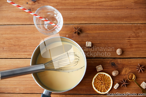 Image of pot with eggnog, ingredients and spices on wood