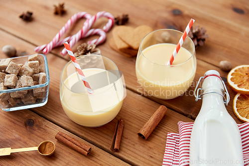 Image of glasses of eggnog, ingredients and spices on wood