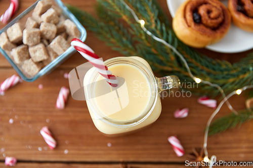 Image of eggnog with candy cane in mug and cinnamon buns