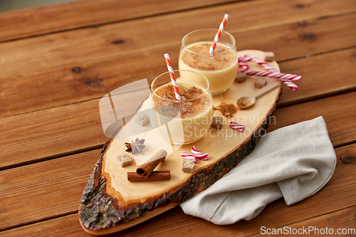 Image of glasses of eggnog, ingredients and spices on wood