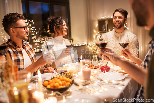 Image of happy friends drinking red wine at christmas party