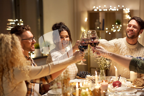 Image of happy friends drinking red wine at christmas party