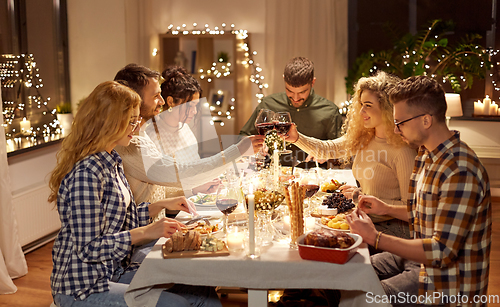 Image of happy friends drinking red wine at christmas party