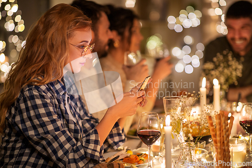 Image of woman with smartphone at dinner party with friends